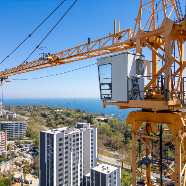 An aerial view of a cityscape showcasing a prominent crane within the urban environment.